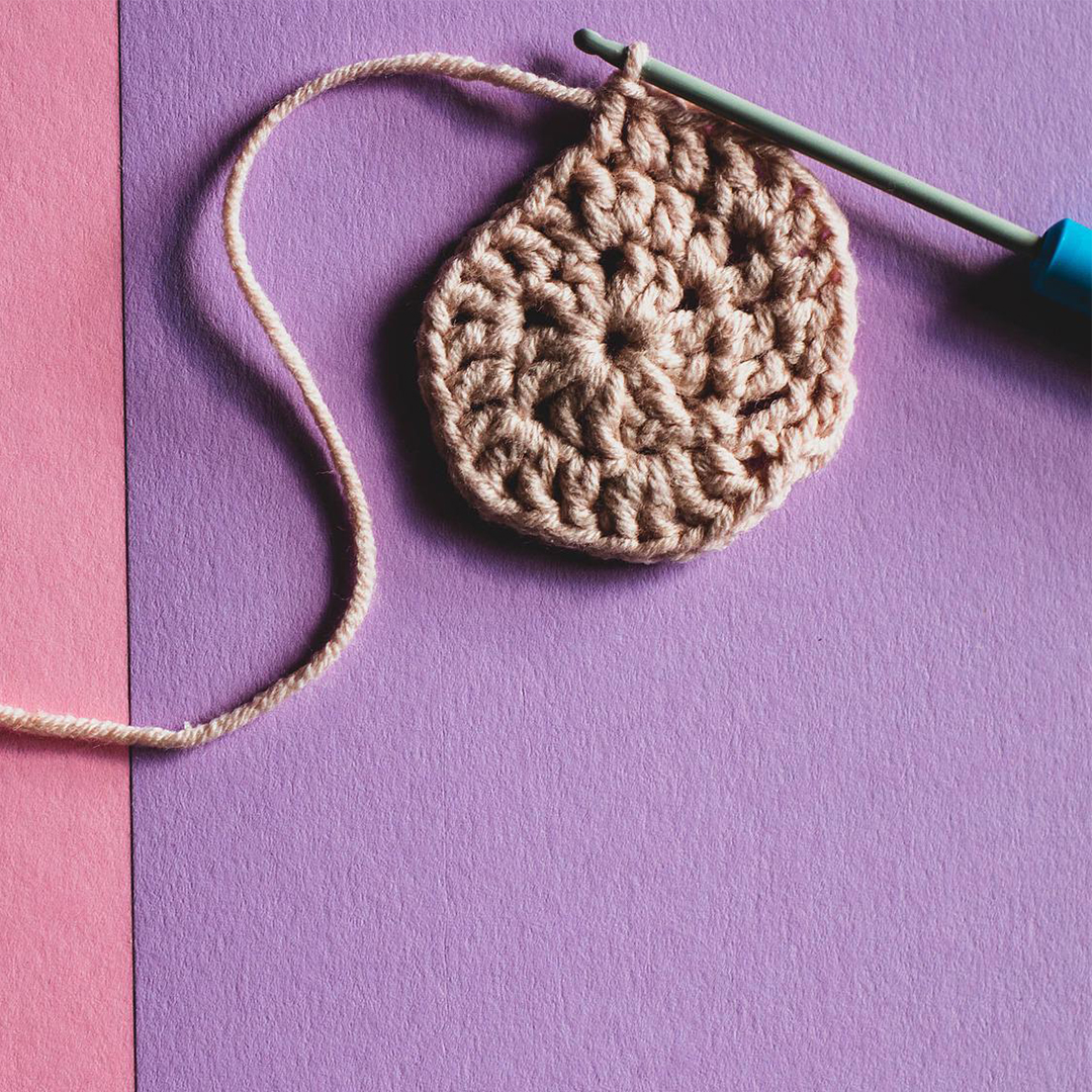purple background with tan yarn crocheted into a small pattern