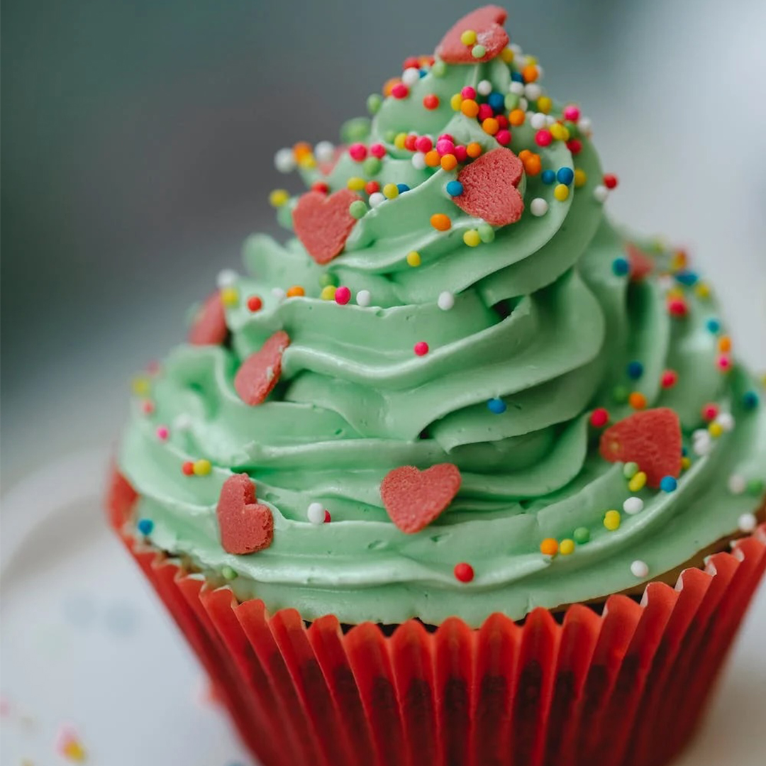 cupcake with green icing and red heart sprinkles