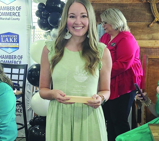 Photo of Tara Irvan holding a plaque from the Chamber of Commerce