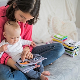 A woman reading to a baby who is in her lap.