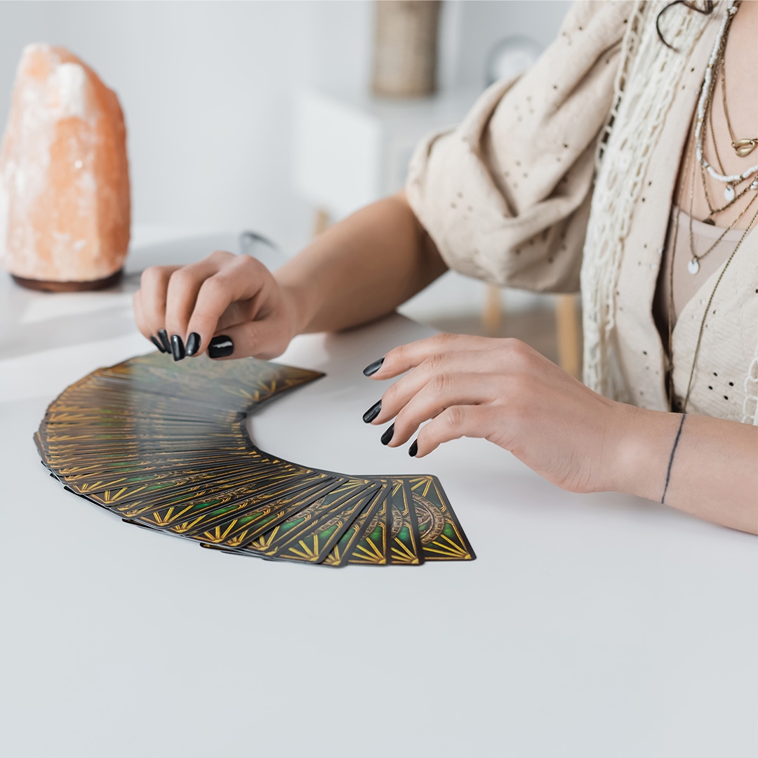 a woman with black nail polish sitting in front of a deck of cards