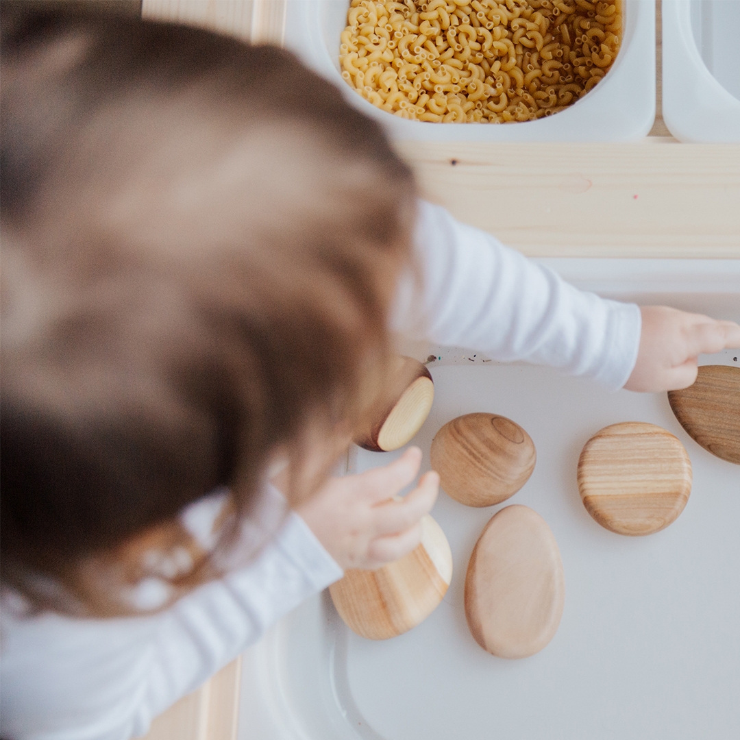 toddler reaching into a bin with textured objects