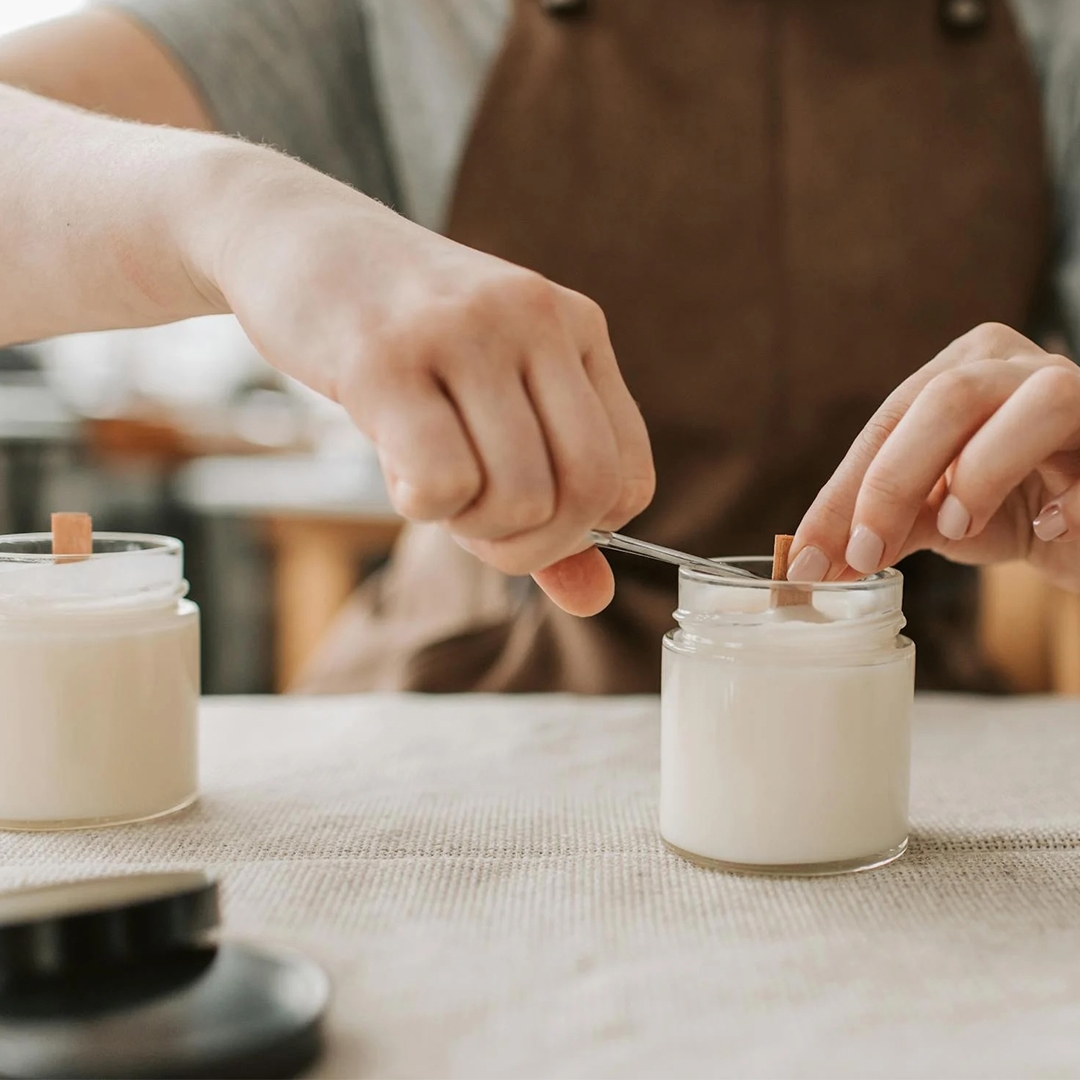 hands adding a wick to a candle